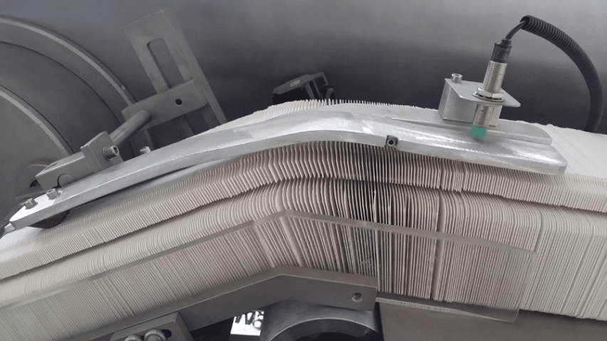 Carton feed chute buffer and level sensor controlling carton supply density on high speed cartoner