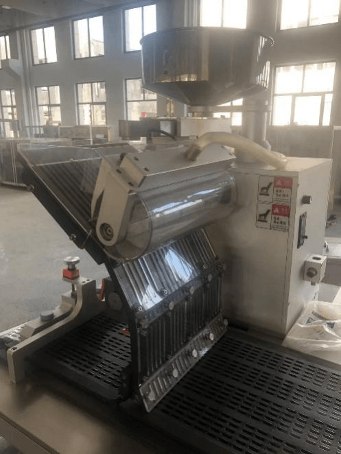 Finished tablet blister packs discharging in line on outfeed conveyor