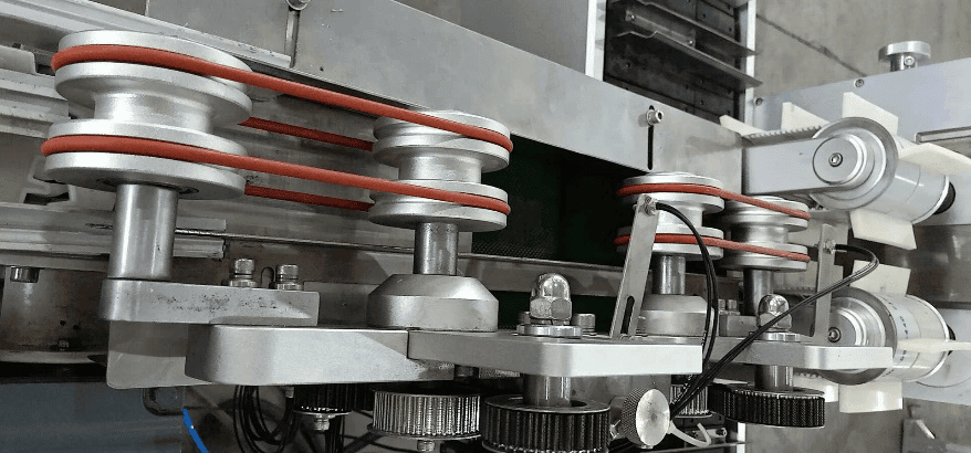 Finished carton output conveyor belt pulley with final lock inspection on high speed cartoner